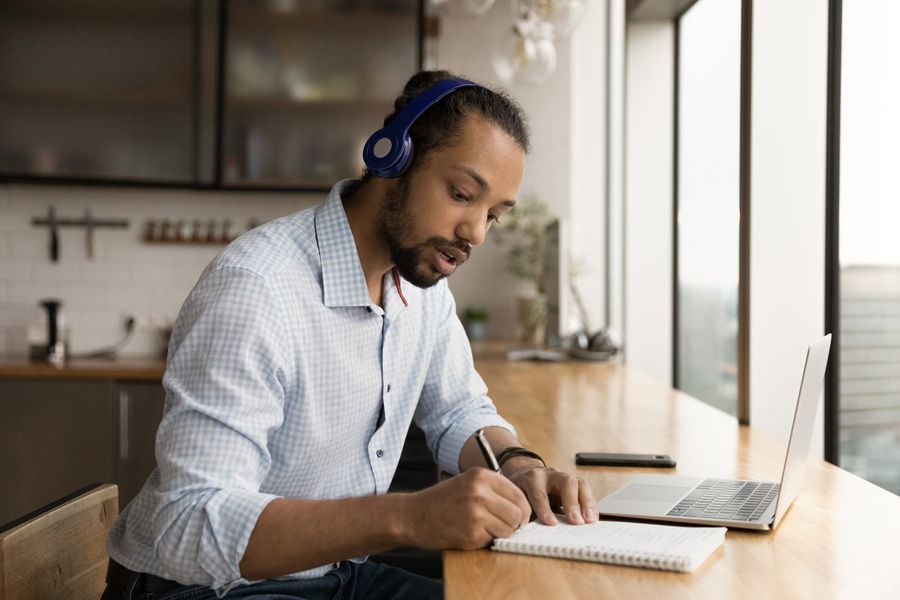 Student taking notes with headphones on